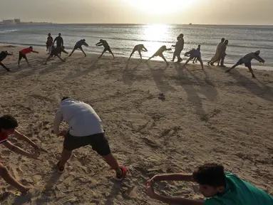 Orang-orang berolahraga di pantai sembari menunggu waktu berbuka puasa selama bulan suci Ramadan, meskipun lockdown karena pandemi COVID-19, di ibu kota Tripoli, Libya pada Jumat (8/5/2020). (Photo by Mahmud TURKIA / AFP)