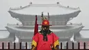 Seorang 'penjaga istana' berdiri untuk turis di depan Istana Gyeongbokgung yang tertutup salju di pusat kota Seoul (19/1/2022). Pihak berwenang di Seoul dan daerah sekitarnya pada Rabu (19/1) tetap waspada karena wilayah ibu kota diperkirakan akan turun salju lebat sepanjang hari. (AFP/Jung Yeon-je)