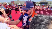 Pembalap Red Bull KTM, Jack Miller, memberikan tanda tangan kepada salah satu penggemar dalam kegiatan MotoGP Hero Walk di Sirkuit Mandalika, Lombok , Minggu (15/10/2023). (Bola.com/Benediktus Gerendo Pradigdo)