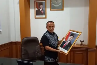 Wakil Ketua DPRD dari Fraksi PDIP, Rojab Asyari, menurunkan bingkai foto resmi Wakil Presiden Gibran Rakabuming Raka. (Liputan6.com/Fira Syahrin)