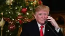 Ekspresi Presiden AS Donald Trump saat berbicara dengan anak-anak di telepon di Palm Beach, AS (24/12). Pada malam natal ini Trump dan istrinya sibuk mendengarkan permintaan anak-anak kepada Sinterklas. (AFP Photo/Nicholas Kamm)