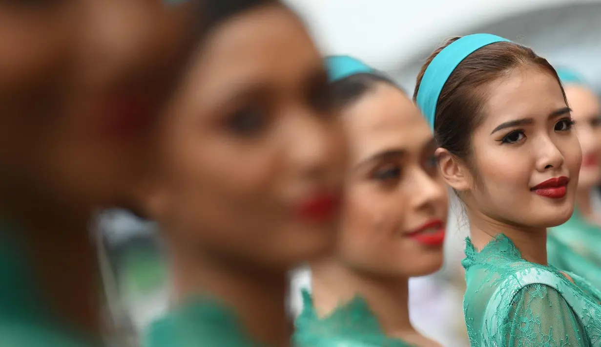 Seorang gadis payung atau grid girl berpose sebelum dimulainya Grand Prix Formula 1 Malaysia di Sepang (1/10). Para gadis payung ini terlihat seksi dengan baju ketat yang dikenakannnya. (AFP Photo/Manan Vatsyayana)