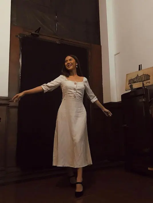 Dress putih yang kasual dipadukan dengan high heels membuat penampilan Nadin sangat anggun. (Instagram/cakecaine).