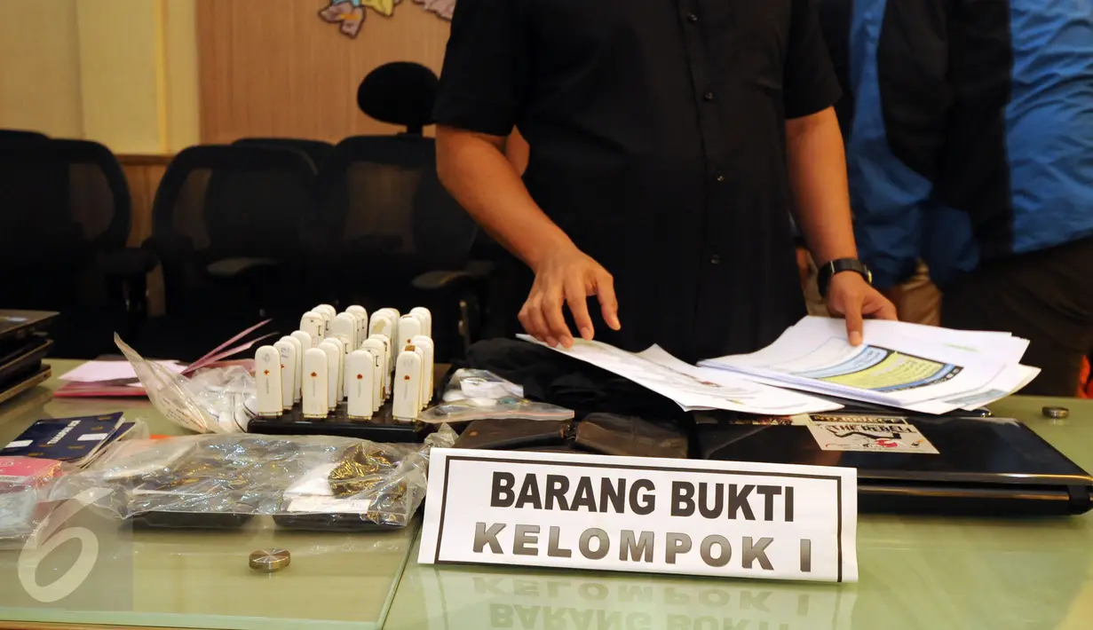 Petugas merapikan barang bukti yang disita dari tersangka aksi penipuan melalui SMS saat rilis di Mapolda Metro Jaya, Sabtu (7/11/2015). Polda Metro Jaya mengungkap kasus penipuan melalui SMS dan meringkus 14 tersangka. (Liputan6.com/Helmi Fithriansyah)