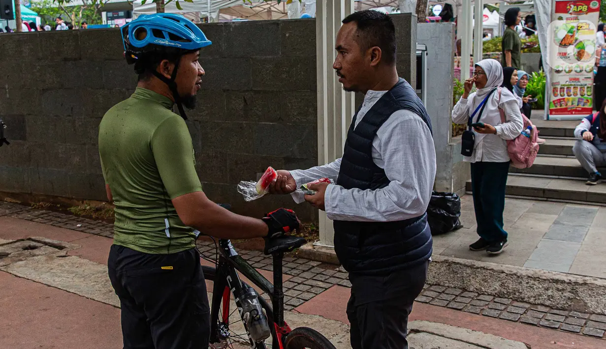 Relawan membagikan buah semangka saat Aksi Damai Aliansi Rakyat Indonesia Bela Palestina di kawasan Sarinah, Jakarta, Minggu (5/11/2023). (Liputan6.com/Faizal Fanani)