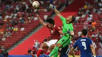 Kiper Singapura, Hassan Sunny (tengah) mencoba menghalau bola dari sundulan pemain Indonesia, Hanis Saghara Putra (kiri) pada pertandingan leg kedua semifinal Piala AFF 2020 di National Stadium, Sabtu (25/12/2021). Indonesia akan bertemu antara Thailand dan Vietnam di babak final. (AFP/Roslan Rahman