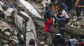 Orang-orang dan tim darurat menyelamatkan seseorang dengan tandu dari bangunan yang runtuh di Adana, Turki, Senin, 6 Februari 2023. Gempa berkekuatan magnitudo 7,8 telah menyebabkan kerusakan signifikan di tenggara Turki dan Suriah. (IHA agency via AP)