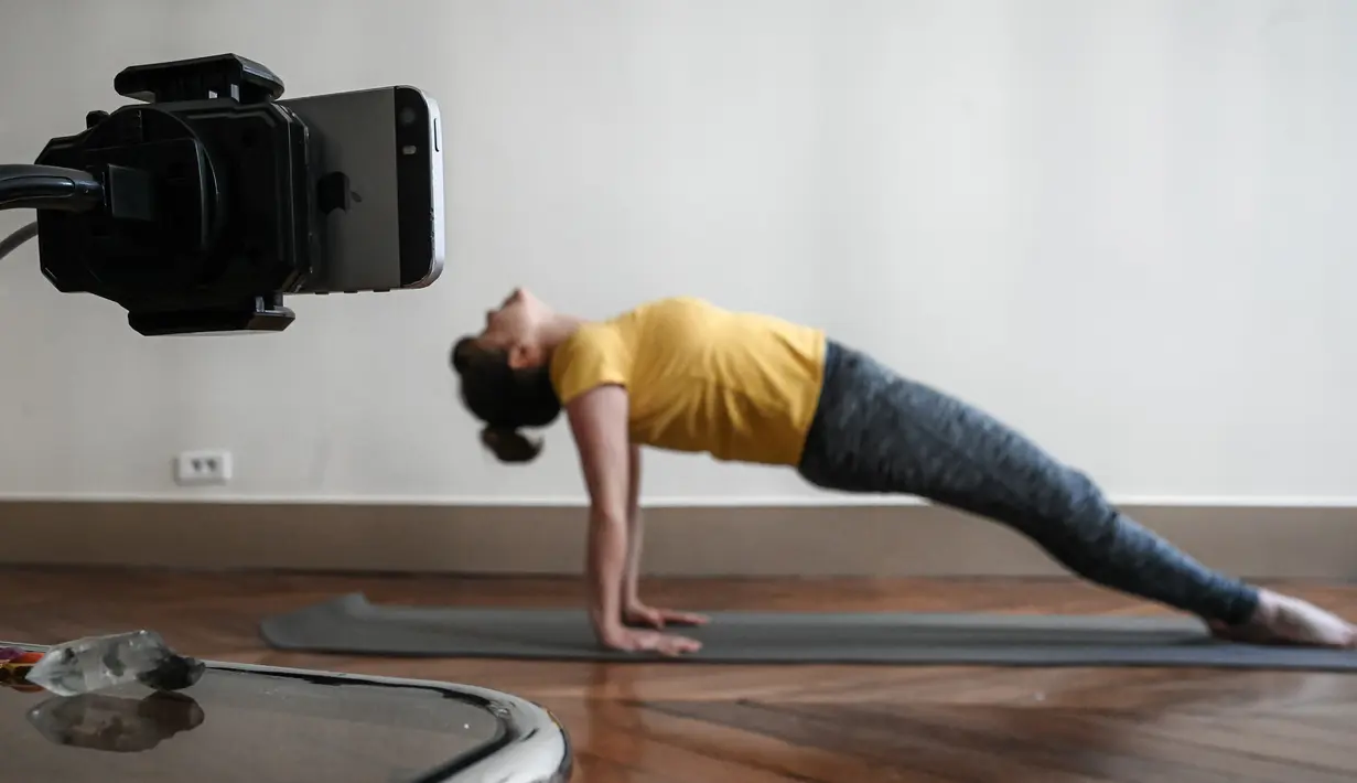 Seorang guru yoga berlatih sebelum mengajar kelas live di akun Instagram-nya pada hari kesembilan belas selama lockdown yang bertujuan untuk membatasi penyebaran infeksi COVID-19 yang disebabkan oleh coronavirus novel di Paris, Prancis (4/4/2020). (AFP/Philippe Lopez)