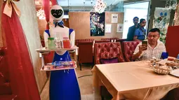Seorang pelayan robot bernama Ruby menyajikan makanan kepada pelanggan di restoran Drink and Spice Magic, Dubai, 26 Juli 2018. Pelayan berupa robot tersebut berhasil menarik antusias pelanggan yang berbondong-bondong mengambil foto. (AFP/GIUSEPPE CACACE)