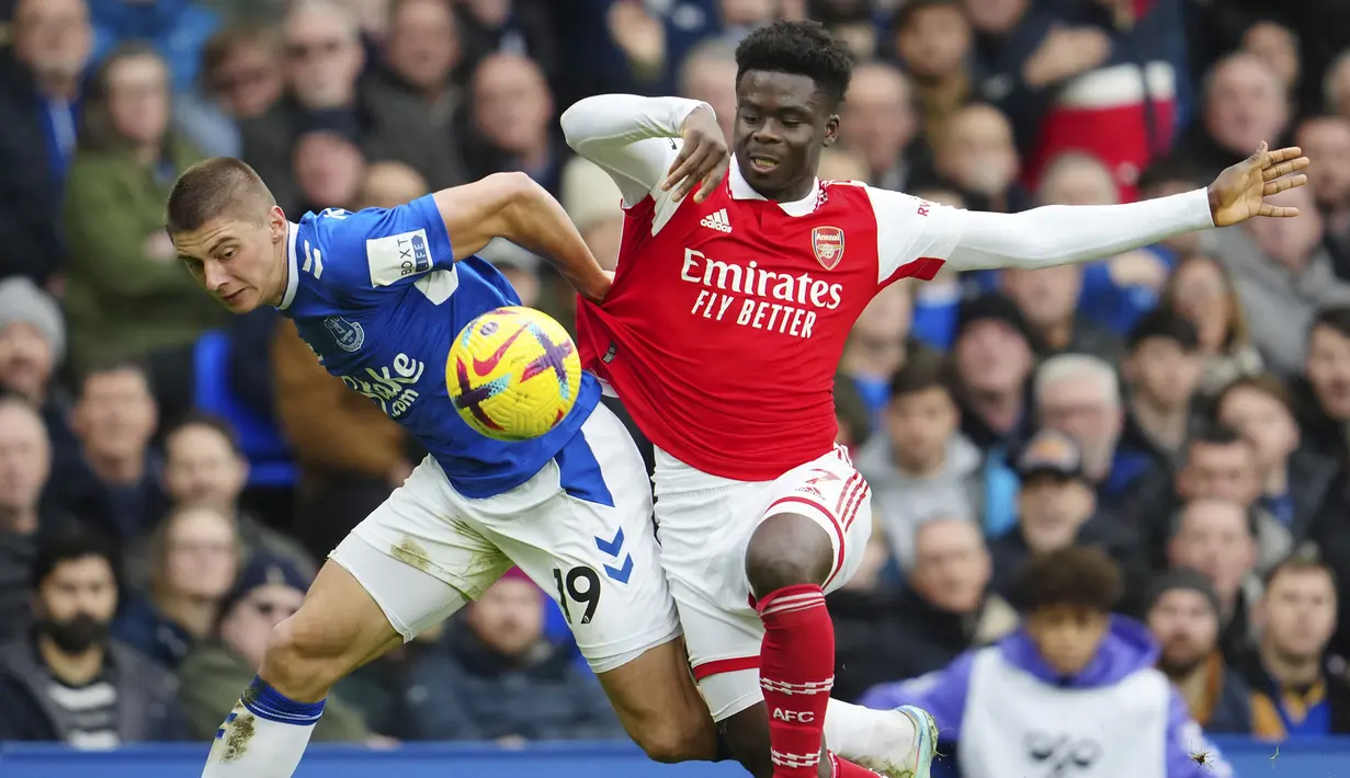 <p>Pemain Arsenal, Bukayo Saka (kanan) berebut bola dengan pemain Everton, Vitaliy Mykolenko pada laga pekan ke-22 Liga Inggris 2022/2023 yang berlangsung di Goodison Park, Sabtu (04/02/2023). Arsenal kalah dengan skor 0-1 dari Everton. (AP/Jon Super)</p>