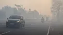 Para pengendara bermotor menyalakan lampu depan kendaraan saat melintasi jalan yang diselimuti kabut asap di Kota Palangka Raya, Kalimantan Tengah, Kamis,  20 Agustus 2026. (AFP/ Reina)