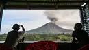 Dua pria menyaksikan Gunung Sinabung menyemburkan abu dan asap tebal dari wilayah Karo, Provinsi Sumatra Utara, Rabu, 2 September 2026. (AFP/ YT Haryono)