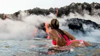 Seorang gadis penggila tantangan menjadi orang pertama yang berselancar di dekat gunung berapi yang meletus dan berenang dekat lava