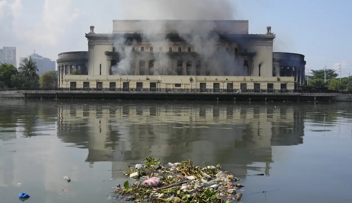 Asap hitam tebal mengepul ratusan meter ke langit saat api memusnahkan Kantor Pos Pusat Manila neo-klasik yang menghadap ke Sungai Pasig. (AP Photo/Aaron Favila)