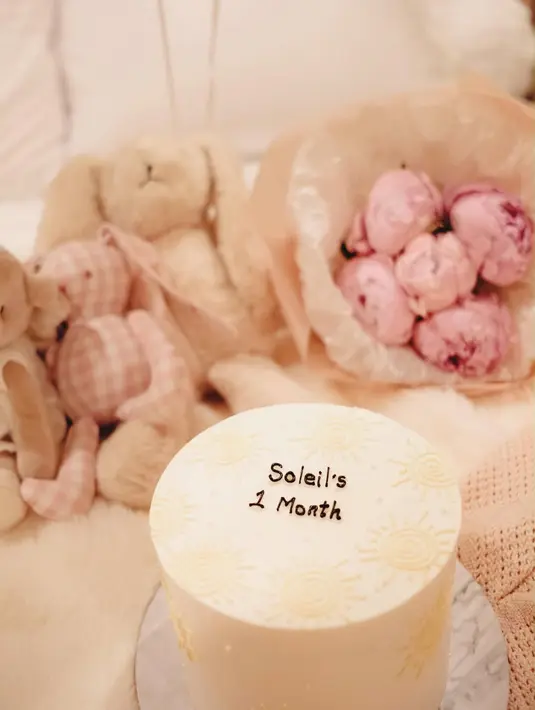Perayaan satu bulan Baby Soleil juga dilengkapi dengan kue berwarna putih berukuran kecil bertuliskan "Soleil's 1 Month". Detail minimalis pada kue tersebut seolah menegaskan konsep perayaan yang intim dan hangat. [@alyssadaguise].