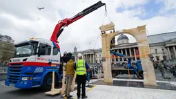 Petugas mengamati alat berat yang meletakkan lengkungan Palmyra berukuran seperti aslinya, sehari sebelum diresmikan di Trafalgar Square, pusat kota London, Senin (18/4). Replika tersebut sebagai simbol perlawanan terhadap terorisme. (Leon Neal/AFP)