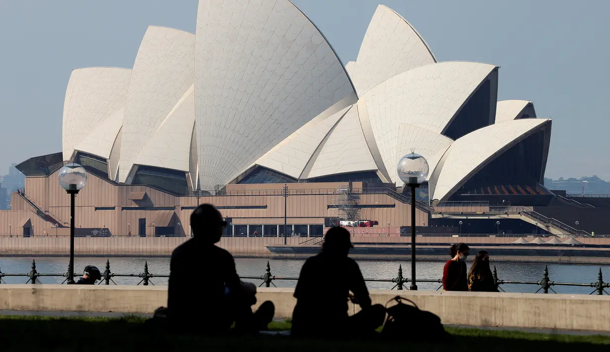 Pengunjung menghabiskan sore mereka di depan Sydney Opera House (21/8/2021). Kota itu memperpanjang penguncian selama dua bulan dan memberlakukan jam malam sebagian untuk menahan wabah virus corona yang menyebar cepat. (AFP/David Gray)
