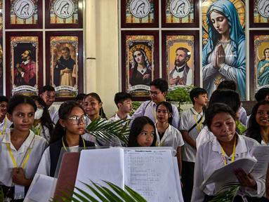 Paduan suara gereja Katolik mempersiapkan daun palem selama prosesi untuk menandai Minggu Palem di Gereja Kelahiran Bunda Maria, yang juga dikenal sebagai Gereja Katolik Kelahiran Santa Perawan Maria, di Surabaya pada 13 April 2025. (JUNI KRISWANTO/AFP)