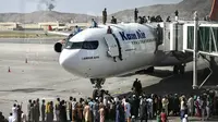 Orang-orang Afghanistan naik ke atas sebuah pesawat saat mereka menunggu di bandara Kabul (16/8/2021). Bandara internasional di Kabul dilanda kekacauan dan kemacetan lalu lintas yang parah. (AFP/Wakil Kohsar)