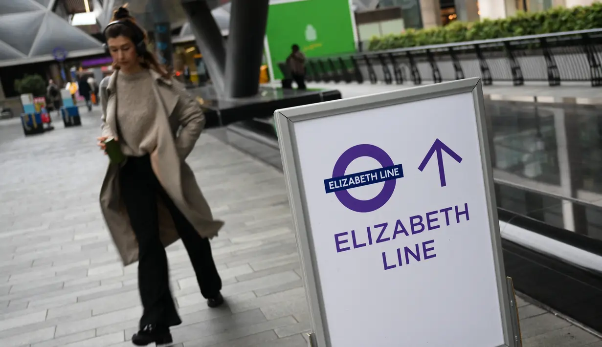 Seorang penumpang berjalan melewati tanda di Stasiun Canary Wharf Elizabeth Line yang baru dibuka di London Timur, Inggris, Senin (7/11/2022). Elizabeth Line baru saja melakukan layanan penuh gabungan untuk pertaman kalinya. (Daniel LEAL / AFP)