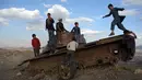 Anak-anak Afghanistan bermain di sisa-sisa tank Soviet di puncak bukit di pinggiran Kabul, Afghanistan (4/3). Mereka sering menghabiskan waktunya dengan bermain di sebuah tank yang sudah hancur dan hasil sitaan para pejuang. (AP Photo/Rahmat Gul)