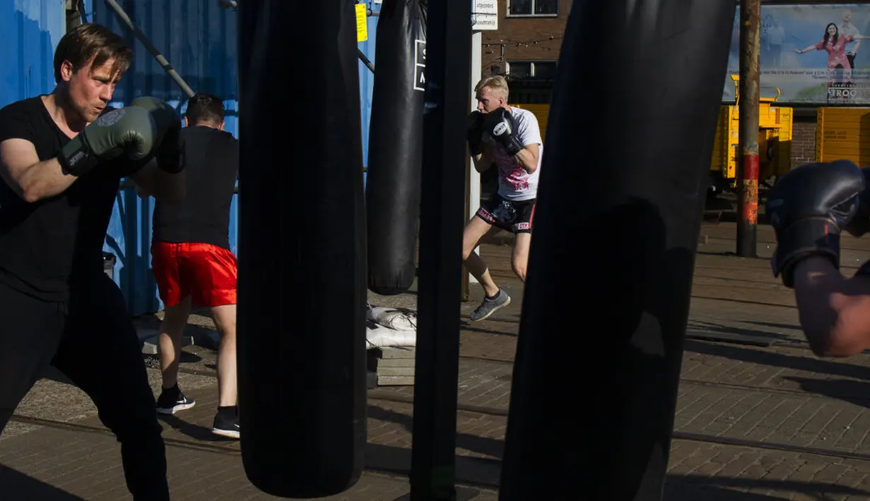 Kickboxer menjaga jarak 1,5 meter mengikuti peraturan protokol kesehatan virus corona COVID-19 pemerintah Belanda saat mereka berlatih di luar ruangan di Amsterdam, Belanda, Selasa (30/3/2021). Kasus COVID-19 di Belanda telah menembus satu juta lebih. (AP Photo/Peter Dejong)