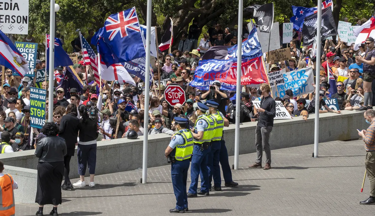 Petugas kepolisian berjaga saat pengunjuk rasa berkumpul di gedung Parlemen Selandia Baru, di Wellington, Selasa (9/11/2021). Ribuan warga Selandia Baru berdemonstrasi memprotes kebijakan vaksin covid-19 dan penguncian (lockdown) yang diterapkan negara itu. (Mark Mitchell/NZ Herald via AP)
