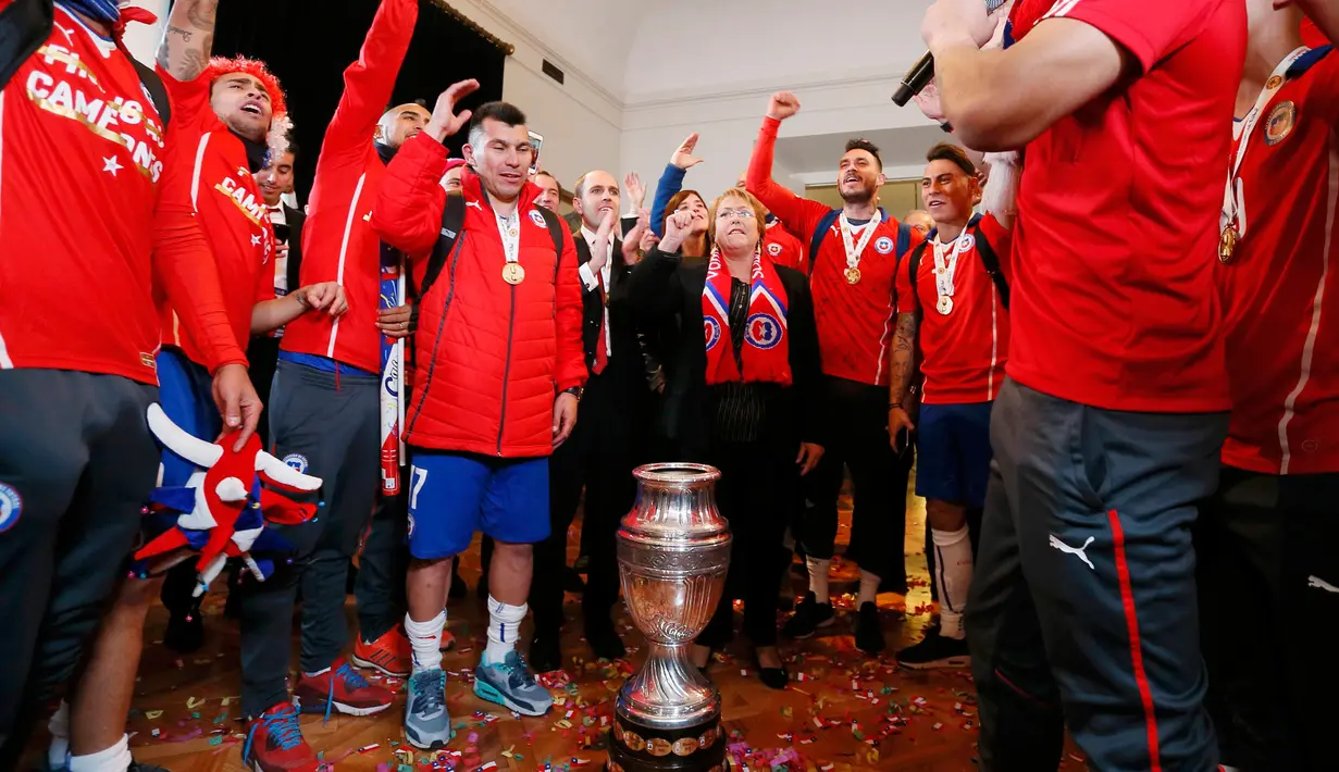 Presiden Chili, Michelle Bachelet dan pemain Chile berpose dengan trofi usai mengalahkan Argentina di final Copa America 2015 di Istana nasional, Chili (4/7/2015). Chili menang lewat adu penalti atas Argentina dengan skor 4-1. (REUTERS/Rodrigo Garrido)