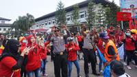 Para polisi menari menemani para demonstran saat peringatan Hari Buruh Sedunia di depan Gedung Sate Bandung.