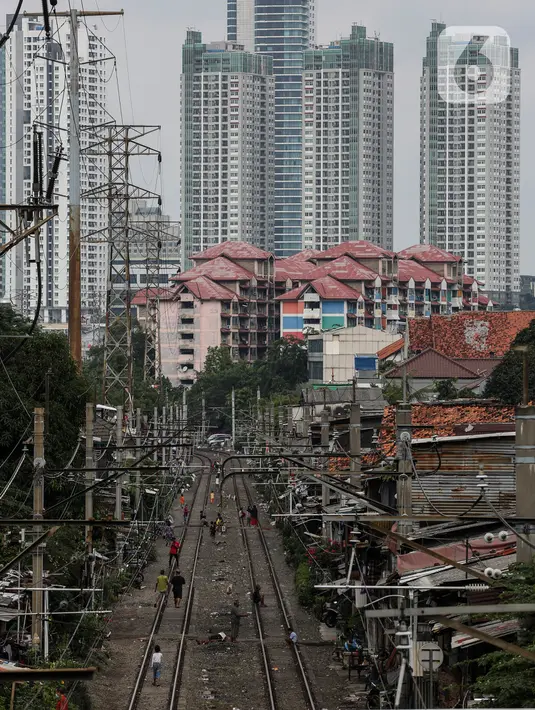 Warga beraktivitas di antara rel kereta dengan latar belakang gedung bertingkat di kawasan Pejompongan, Jakarta, Selasa (5/1/2021). Pemerintah mengalokasikan anggaran untuk PEN 2021 sebesar Rp403,9 triliun, anggaran ini naik dari rencana sebelumnya sebesar Rp372,3 triliun. (Liputan6.com/Johan Tallo)