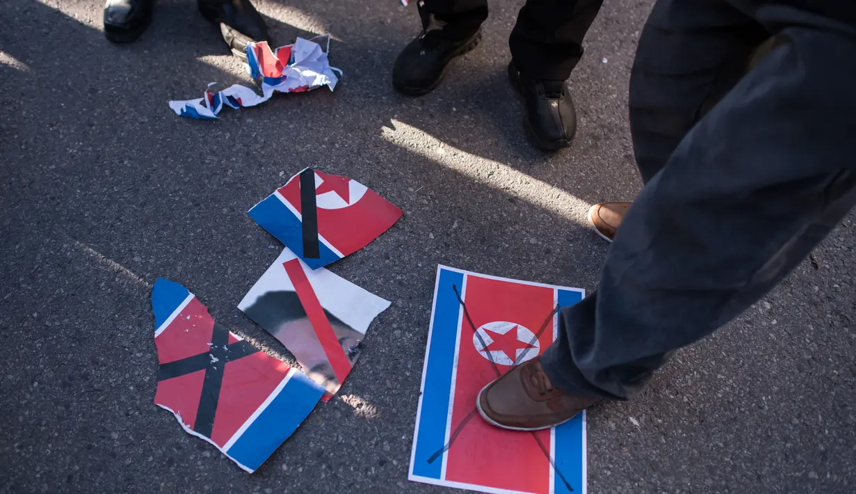 Bendera Korut diinjak pengunjuk rasa anti-Korea Utara saat menggelar aksi di pelabuhan Mukho di Donghae, Korsel (6/2). Mereka melakukan aksi menyambut rombongan seni dari Korut yang akan tampil di Olimpiade Musim Dingin Pyeongchang 2018. (AFP/Ed Jones)