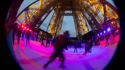 Seorang wisatawan menikmati keseruan bermain ice skating di sebuah arena yang dibuka di lantai 1 Menara Eiffel, Paris, 19 Desember 2016. Wisatawan bisa meluncur di es sambil menikmati pemandangan indah dari atas kota Paris. (AFP PHOTO/JOEL SAGET)