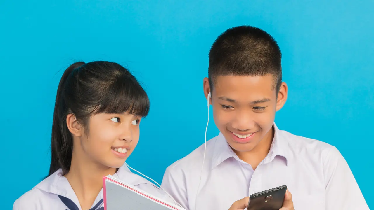 Dua orang siswa sedang mendengarkan HP bersama dengan menggunakan headset (Foto Dok: Freepik/jcomp)