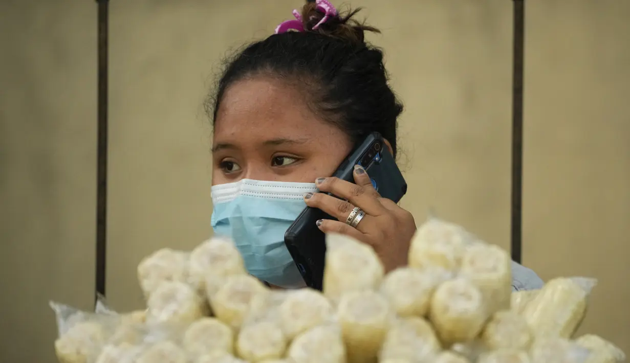 Seorang pedagang menggunakan smartphone-nya saat menunggu pelanggan di kota Quezon, Senin (17/1/2022). Pemerintah Filipina melarang orang yang belum menerima vaksin COVID-19 untuk naik transportasi umum di ibu kota Manila menyusul lonjakan kasus covid varian omicron. (AP Photo/Aaron Favila)