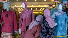 Wanita Muslim melihat ke sebuah toko yang menjual pakaian budaya Malaysia yang disebut baju melayu dan baju kurung menjelang  Idul Fitri yang menandai berakhirnya bulan suci Ramadan di Kuala Lumpur (13/5/2020). (AFP/Mohd Rasfan)