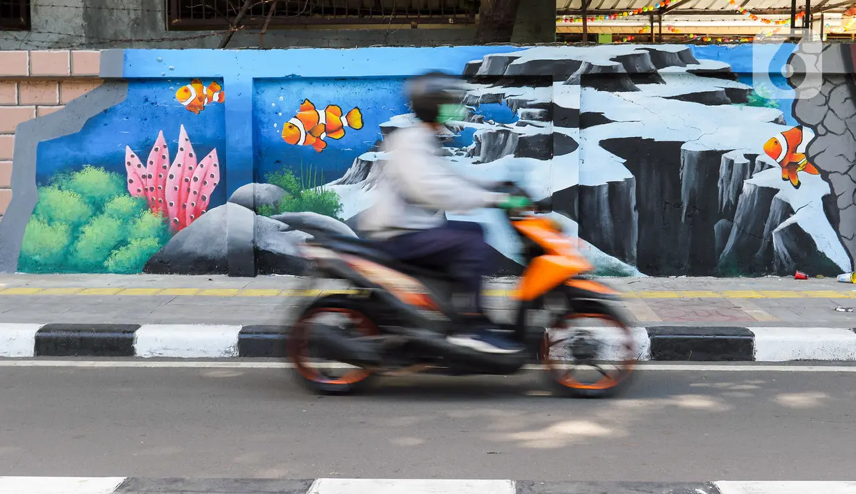 Pengendara sepeda motor melintas di samping mural bertema biota laut yang menghiasi dinding di kawasan Cideng, Jakarta, Rabu (29/11/2023). Mural dibuat guna memperindah sekaligus penataan kawasan Kelurahan Cideng, Jakarta Pusat. (Liputan6.com/Herman Zakharia)