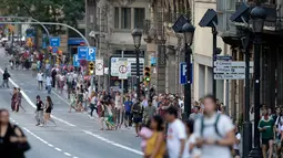 Warga dan turis berjalan pasca mobil van menabrak kerumunan orang  di Jalanan Las Ramblas, Barcelona, Spanyol (17/8). Saksi mata mengatakan, sebelum menabrak kerumunan, van melaju secara zig zag dengan kecepatan tinggi. (AP Photo/Manu Fernandez)