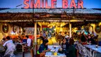 Orang-orang duduk di sebuah bar , saat para turis memanfaatkan program "Kotak Pasir Phuket" untuk pengunjung yang divaksinasi penuh terhadap virus corona Covid-19 di pulau Phuket Thailand (25/10/2021). (AFP/Mladen Antonov)
