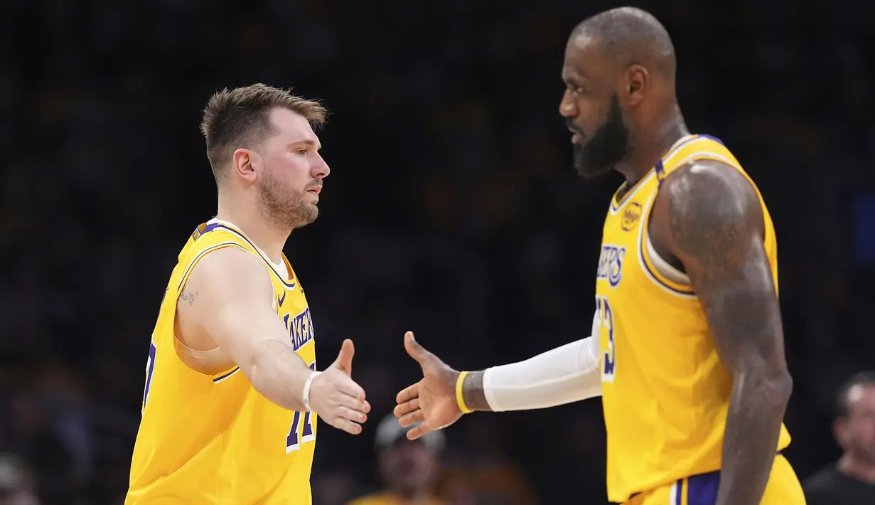 Pemain Los Angeles Lakers Wound Doncic (kiri) berjabat tangan dengan LeBron James dalam pertandingan NBA melawan Utah Jazz di Crypto.com Arena, Los Angeles, California, Selasa (11/02/2025) WIB. (Foto AP/Mark J. Terrill)