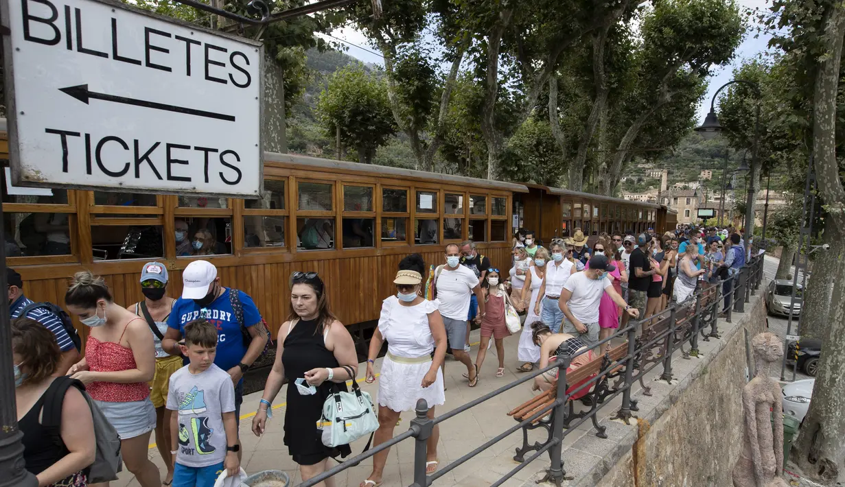 Penumpang tiba untuk menaiki kereta Palma-Soller di Soller di Pulau Balearic Spanyol Mallorca (14/7/2021). Diresmikan pada tahun 1912, jalur kereta api Palma-Soller adalah salah satu rute tertua yang masih beroperasi di Spanyol. (AFP/Jaime Reina)