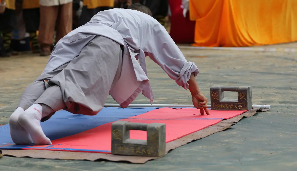 Seorang biksu menunjukkan kemampuann push up dengan dua jari selama kompetisi seni bela diri '72 Arts of Shaolin' di kuil Shaolin di Provinsi Henan, China, 30 Juli 2017. Kompetisi ini menampilkan para jago kungfu yang memamerkan kekuatan fisik. (STR AFP)