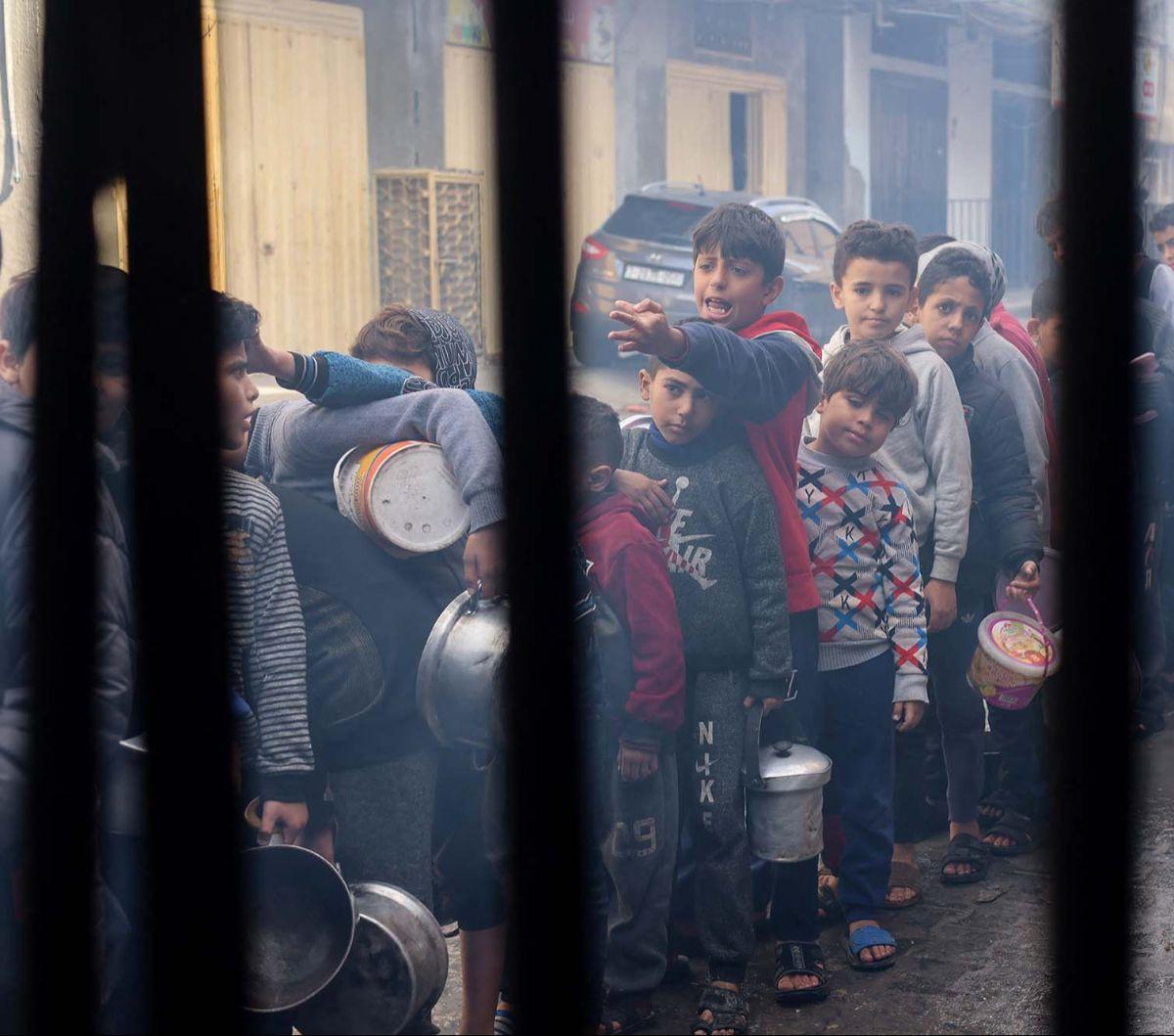Serangan brutal Israel yang terus berlanjut membuat Jalur Gaza terperosok dalam bencana kelaparan. Sebagaimana yang terlihat di sebuah dapur umum di Rafah, Gaza selatan, Kamis (14/12/2023), sejumlah anak mengantre panjang demi mendapatkan makanan.