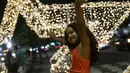 Seorang anak berpose dengan latar belakang lampu Natal di sepanjang pantai Copacabana, di Rio de Janeiro, Brasil (11/12/2021). Jelang perayaan Natal, taman dan pantai dihiasi lampu-lampu yang indah. (AP Photo/Bruna Prado)
