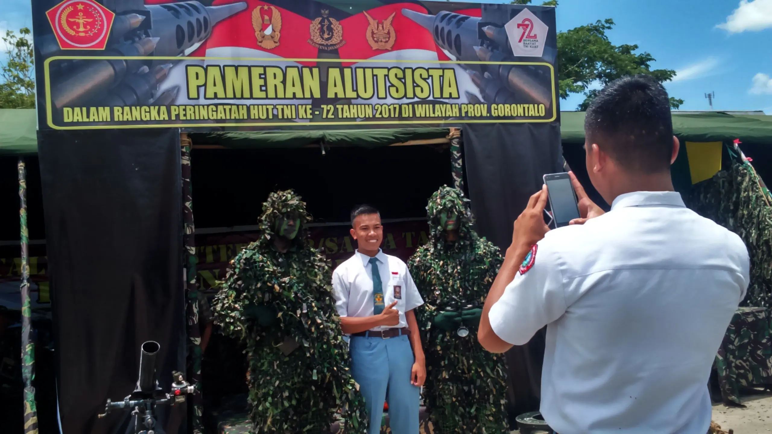 Sejumlah siswa berfoto bersama prajurit saat pameran alusista di peringatan HUT ke-72 TNI di Gorontalo. (Liputan6.com/Aldiansyah Mochammad Fachrurrozy)