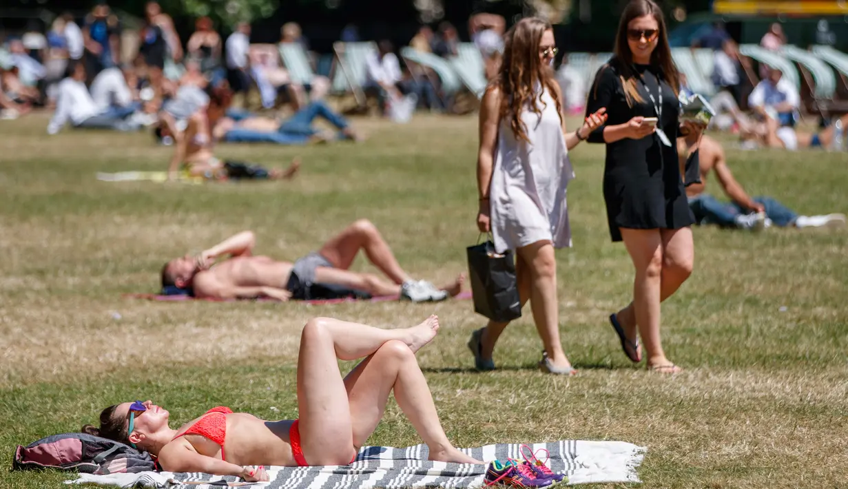 Sejumlah warga Inggris berjemur di atas rumput sambil menikmati sinar matahari di Green Park, London, Senin (25/6). Pada Juli 2018, suhu di ibu kota London tercatat 29.1 derajat Celcius dan diprediksi akan mencapai 30 derajat Celcius. (AFP/Tolga Akmen)