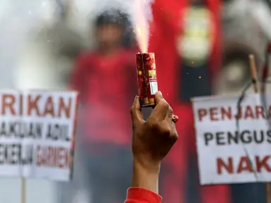 Buruh menyalakan bom asap saat menutup aksi Hari Buruh Internasional di Jalan Medan Merdeka Barat, Jakarta, Rabu (5/1/2019). Buruh dari berbagai organisasi merayakan Hari Buruh Internasional di Kawasan Silang Barat Daya Monas. (Liputan6.com/Helmi Fithriansyah)