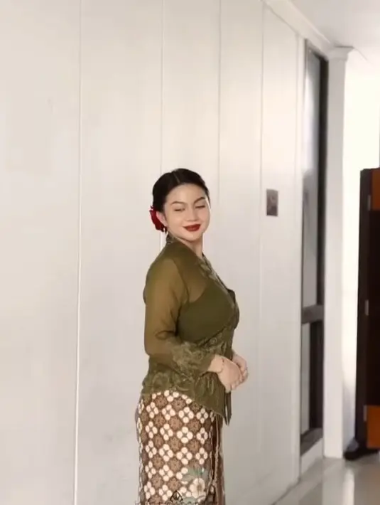 Ariel mengenakan atasan kebaya berwarna hijau dengan kain tenun sebagai bawahan. [Instagram/arieltatum]