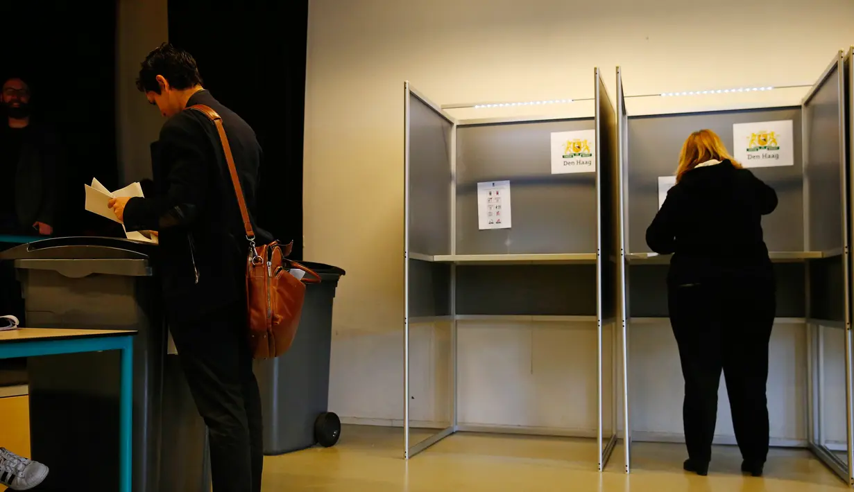 Pemilih memasukkan surat suara ke kotak suara saat pemilihan umum Belanda di sebuah Tempat Pemungutan Suara (TPS) di Den Haag, Rabu (15/3). Ada yang unik dalam pemilu Belanda itu, dimana tempat sampah disulap menjadi kotak suara. (AP Photo/Peter Dejong)