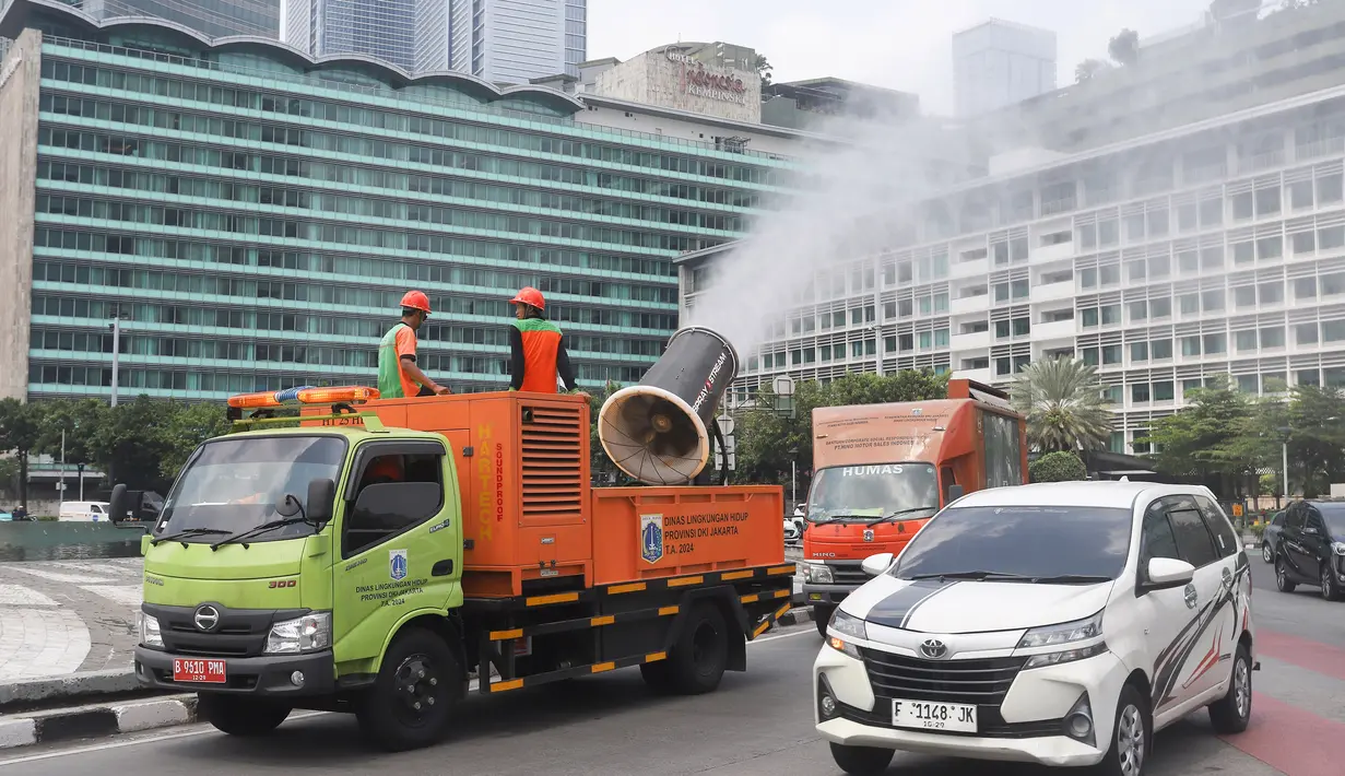 Petugas Dinas Lingkungan Hidup DKI Jakarta menyemprotkan kabut air (water mist) di sepanjang Jalan MH Thamrin, Jakarta Pusat, pada Senin (22/9/2025). (merdeka.com/Arie Basuki)