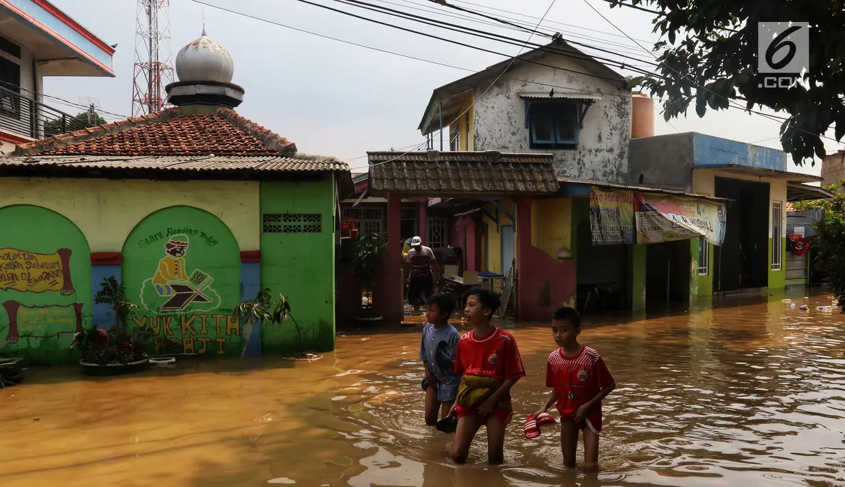 Anak-anak melintasi banjir yang melanda kawasan bantaran kali Cisadane, Tangerang, Jumat (26/4). Banjir kiriman setinggi 2 meter sempat melanda kawasan akibat curah hujan yang tinggi di bogor membuat derasnya air mengalir jauh sampai ke tempat ini. (Liputan6.com/Johan Tallo)
